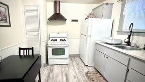 Eine kompakte Küche mit Herd, Backofen, Kühlschrank und einem Esstisch mit Stühlen.