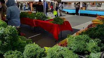 A market stall with various vegetables displayed on a red table.