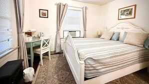 Ein Schlafzimmer mit Bett, Schreibtisch und einem fensterbepflanzten Fenster.