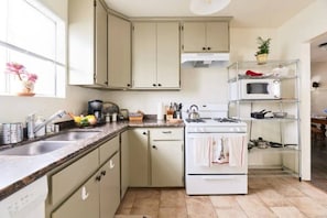 A kitchen with a stove, sink, cabinets, and a microwave. - Beautiful 2 bedroom Victorian home (Vallejo)