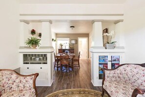 A dining area with a wooden table and chairs, a white fireplace, and a hallway leading to another room. - Beautiful 2 bedroom Victorian home (Vallejo)