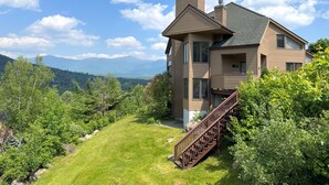 Ein zweistöckiges Haus mit einem markanten Schornstein, einem Balkon und einer Treppe, die zum oberen Stockwerk führt.