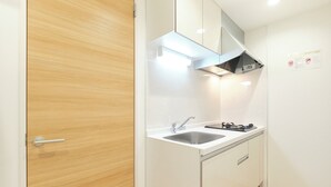 A compact kitchen with a sink, stove, and a wooden door. - Gaia BOSCO by Tranova (Tokyo)