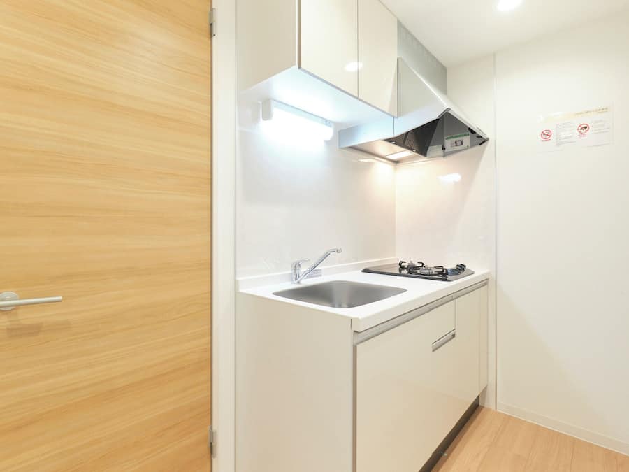 A compact kitchen with a sink, stove, and a wooden door.
