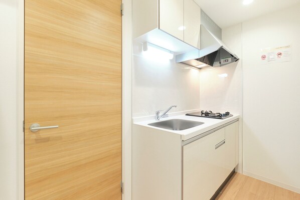 A compact kitchen with a sink, stove, and a wooden door. - Gaia BOSCO by Tranova (Tokyo)