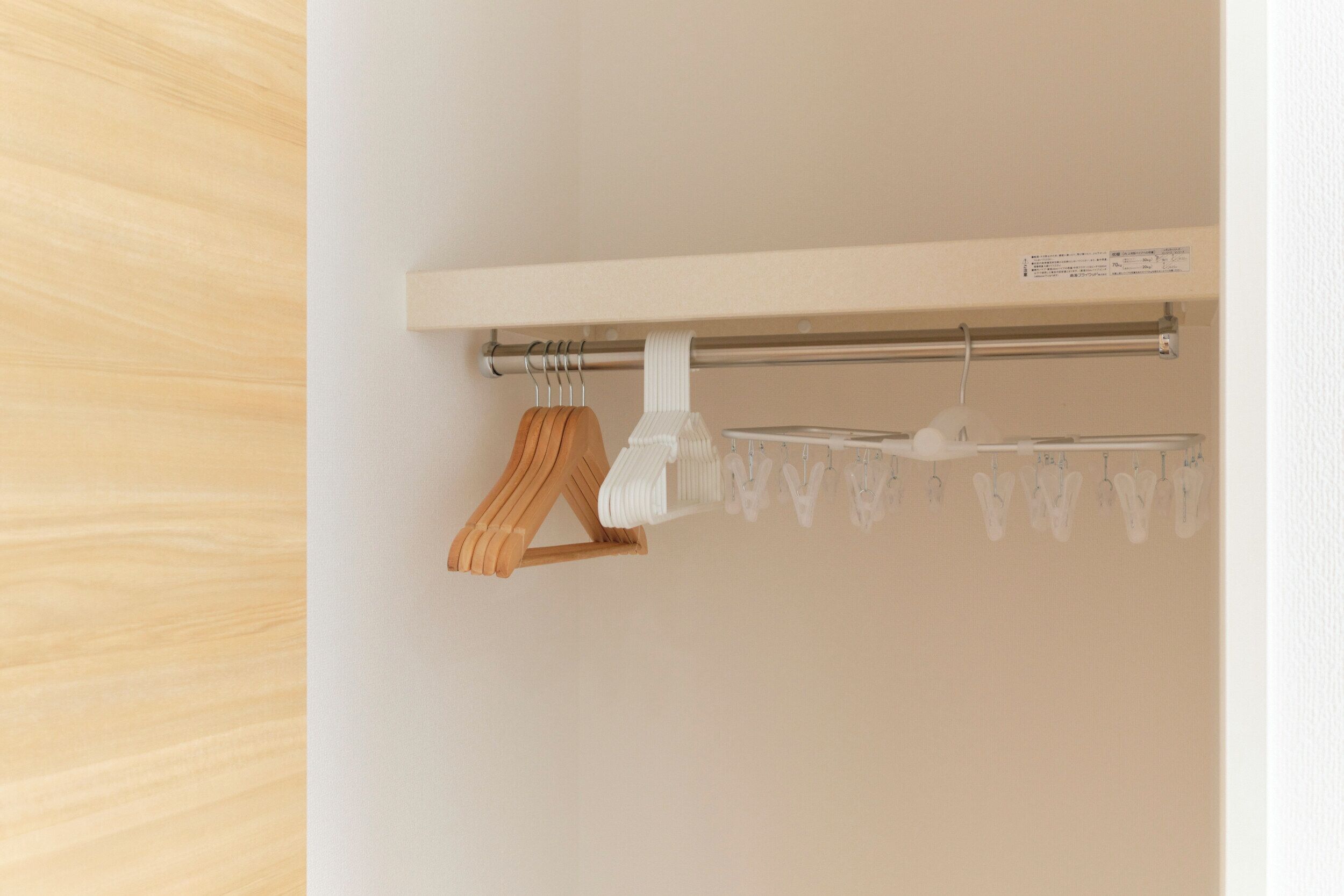 A wooden hanger and a metal drying rack with clothes hanging on it.