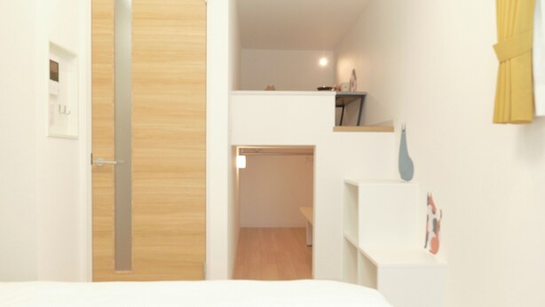 A modern hotel room with a wooden door, a small desk, and a shelf with a picture. - Gaia BOSCO by Tranova (Tokyo)