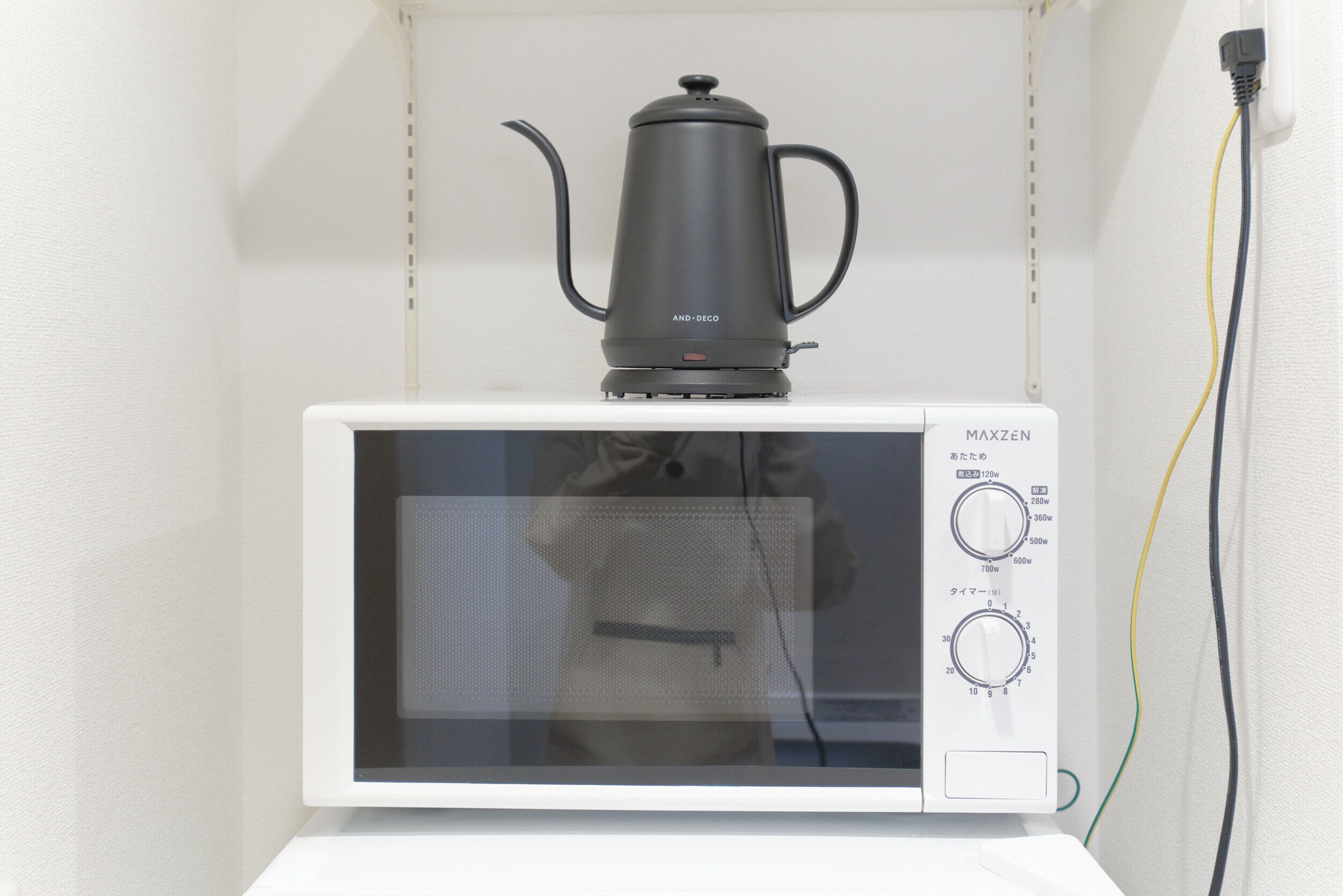 A microwave with a black coffee pot on top, a control panel with power and timer settings, and a visible power cord.