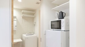 A compact kitchen with a microwave, a small refrigerator, and a washing machine. - Gaia BOSCO by Tranova (Tokyo)