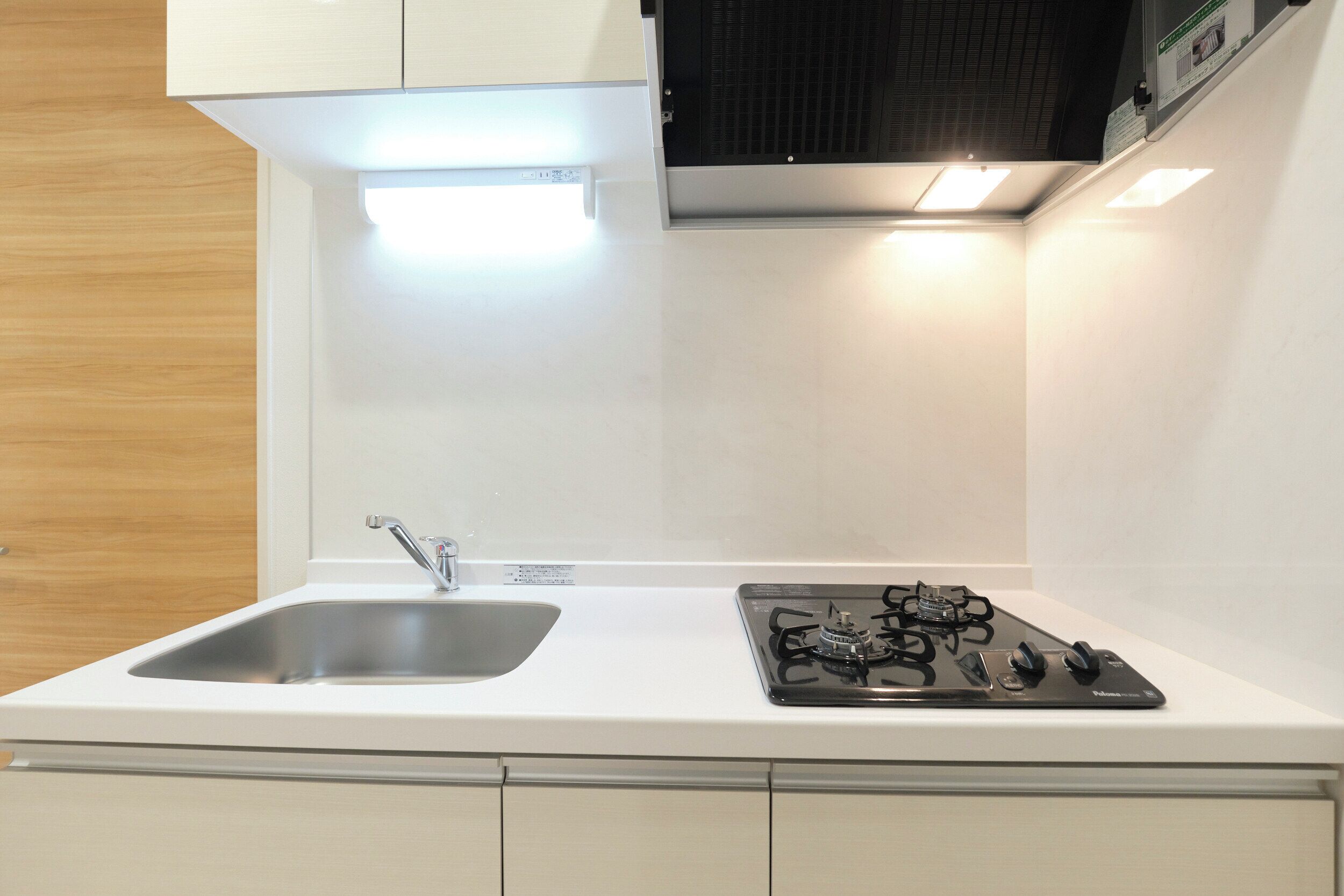 A modern kitchen with a white countertop, stainless steel sink, and a gas stove.