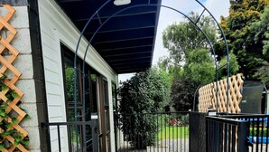A stone-paved entrance with a black metal gate, a wooden lattice on the left, and a covered area with a ceiling light. - Whakatā Place - Peaceful, Chic, Central Retreat Near Beaches, Parks & Adventure! (Motueka)