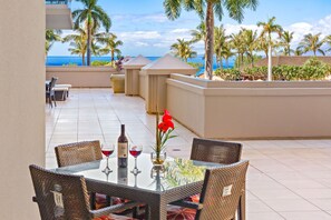 Eine Terrasse mit Tisch für zwei Personen, mit Blick auf einen Strand mit Palmen und einem klaren Himmel.
