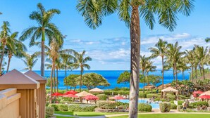 A resort with a pool area, palm trees, and a view of the ocean.