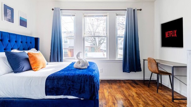 A hotel room with a bed, a desk, and a window with curtains. - 2BR Apt| Free Pkng| Netflix|NJ Train| Pets |5 pple (Newark)