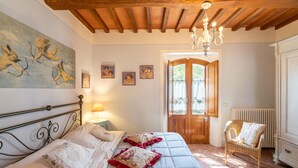 Ein Schlafzimmer mit einem Bett, einem Sessel, einer Tür und einem Bild an der Wand.