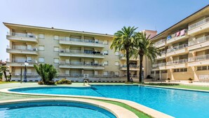 Une piscine au design incurvé, entourée d’une pelouse verdoyante et de palmiers.