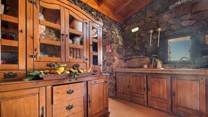 A rustic kitchen with wooden cabinets, a stone wall, and a wooden countertop. - House  Finca  Relax cercadillo (santa Ursula)