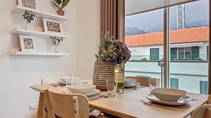 Et spiseområde med et bord dækket til to personer, en vase med blomster og en vinflaske.