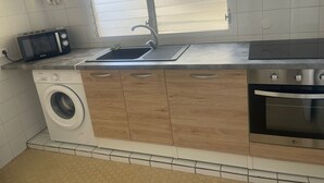 Une cuisine compacte équipée d’un lave-linge, d’un four à micro-ondes, d’un évier et d’une cuisinière.