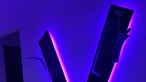 Une installation lumineuse moderne en forme de X, fixée sur un mur.
