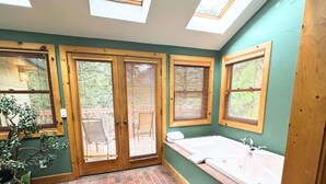 A bathroom with skylights, a bathtub, and wooden-framed windows. - Wood Nymph Suite at RiverSong Inn in Estes Park - Riverside in Rocky Mountain National Park (Estes Park)