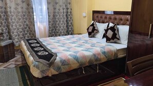 A neatly arranged bedroom with a bed, a nightstand, a wardrobe, and a window with curtains. - Hotel parichit (Namchi)