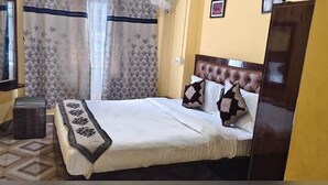A neatly arranged bedroom with a bed, a bedside table, and a mirror. - Hotel parichit (Namchi)