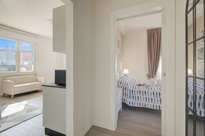 A hotel room with a bed, a TV, a sofa, and a window. - La Maison Fleurie Appartamento Glicine 2BR Walk Beach, Desenzano Del Garda, Italy (Desenzano Del Garda)