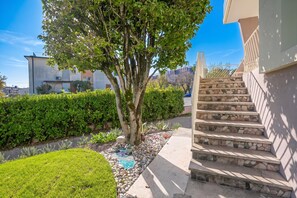 A residential area with a tree, a well-maintained lawn, and a stone staircase leading to a building.