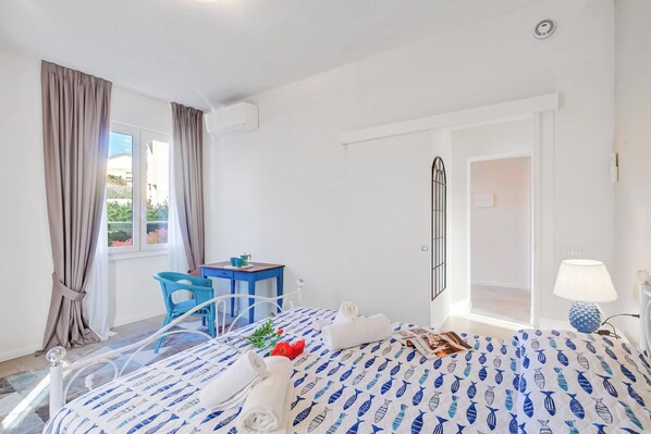 A hotel room with a bed, a desk, a chair, and a door leading to a balcony.