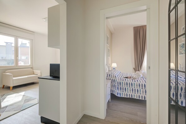 A modern bedroom with a bed, a TV, and a window.