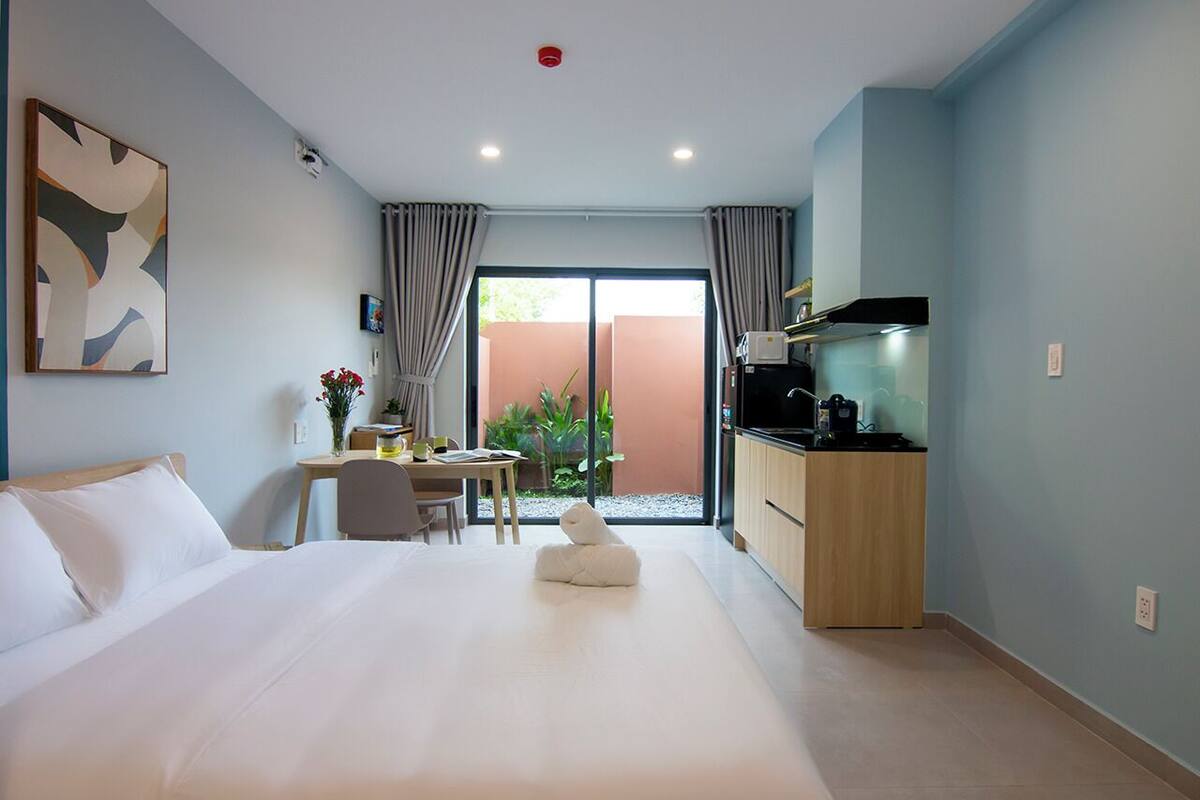 Ein Hotelzimmer mit einem großen Bett, einem Schreibtisch, einem Sessel, einem Fernseher und Blick ins Freie.