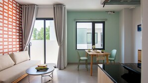 A modern living room with a sofa, a round coffee table, and a dining area with a table and chairs. - ORA Serviced Apartments - Binh Duong New City (Ho Chi Minh City)