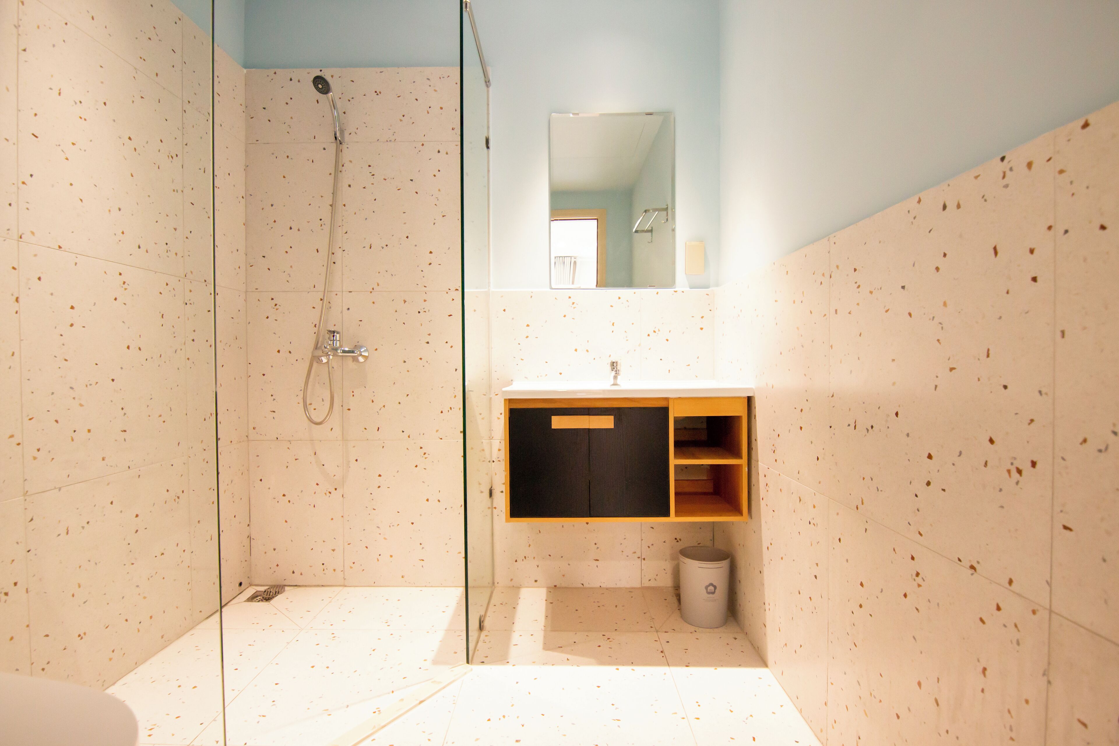 A modern bathroom with a glass shower enclosure, a wooden vanity, and a mirror above the sink.