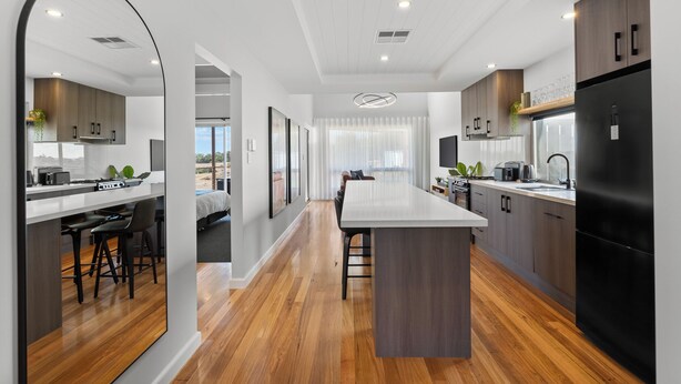 Una cocina moderna con una isla central, piso de madera y vistas al exterior.
