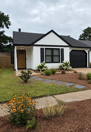A single-story house with a front porch, a garage, and a well-maintained lawn.