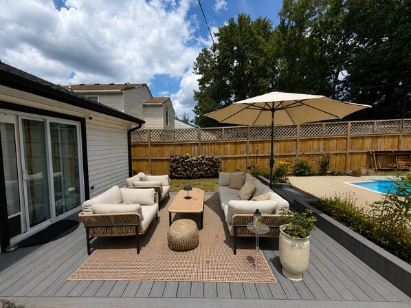 A patio with outdoor furniture, a pool, and a wooden fence.