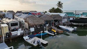 Un puerto deportivo con barcos amarrados, edificios con techo de paja y un remolque al frente.
