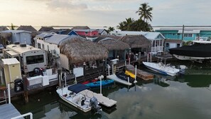 A marina with boats docked, thatched-roof structures, and a trailer in the foreground. - Nice Water Front Tiny home w AC, WiFi include boat ramp & 20ft dock in KeyLargo (Key Largo)