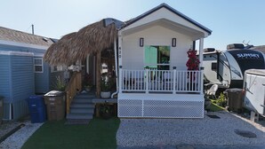 A small, single-story house with a porch, a thatched roof, and a green door. - Nice Water Front Tiny home w AC, WiFi include boat ramp & 20ft dock in KeyLargo (Key Largo)