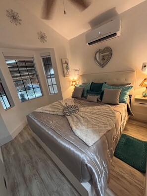 A bedroom with a large bed, a ceiling fan, an air conditioning unit, a window with a view, and a decorative mirror. - Nice Water Front Tiny home w AC, WiFi include boat ramp & 20ft dock in KeyLargo (Key Largo)