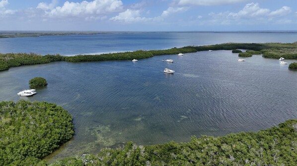 A coastal area with boats on a calm sea, surrounded by dense greenery. - Nice Water Front Tiny home w AC, WiFi include boat ramp & 20ft dock in KeyLargo (Key Largo)
