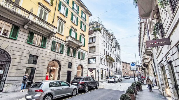 A street view with parked cars, a pedestrian, and buildings with storefronts. - Sant' Andrea Fashion Suite by Interhome (Milan)