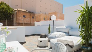 A rooftop terrace with a bed, seating area, and a potted plant. - Apartment with a spectacular terrace in the center (Málaga)