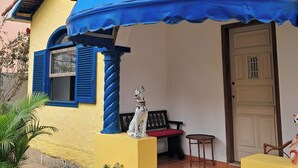 A house with a blue awning, a dog statue, and a red bench.