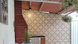 A patio area with a table and chairs, patterned tiles, a hanging plant, and a brick wall.