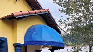 A yellow building with a blue awning, a small porch, and a view of a body of water.