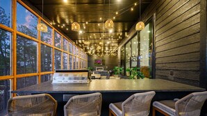 Uma área de bar com cadeiras de vime, balcão e luminárias pendentes.