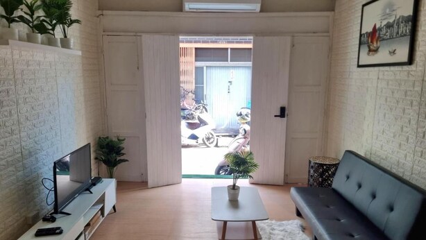 Een woonkamer met een bank, televisie en een plantentafel.