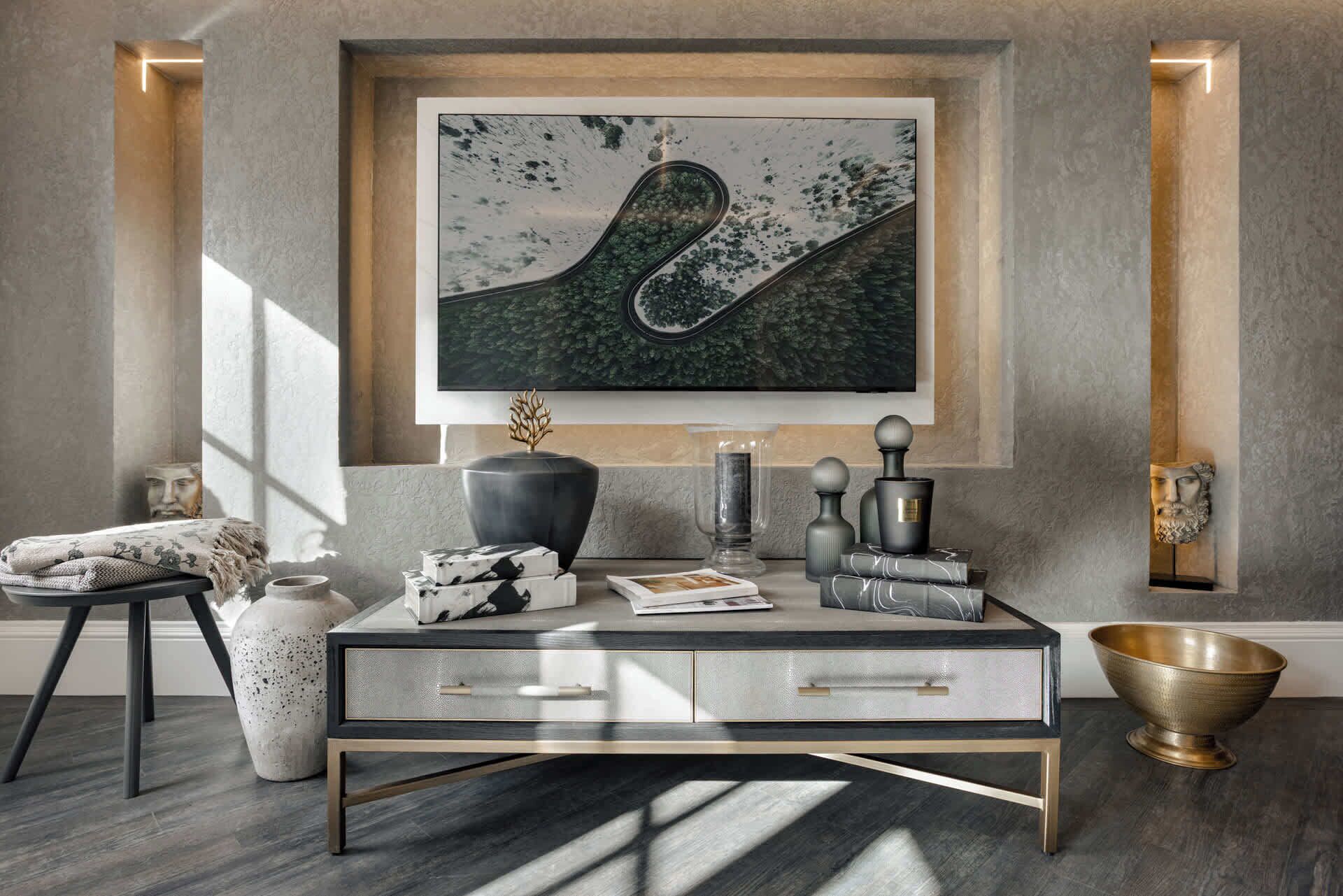A modern living room with a glass coffee table, a framed abstract painting, and a decorative bowl.